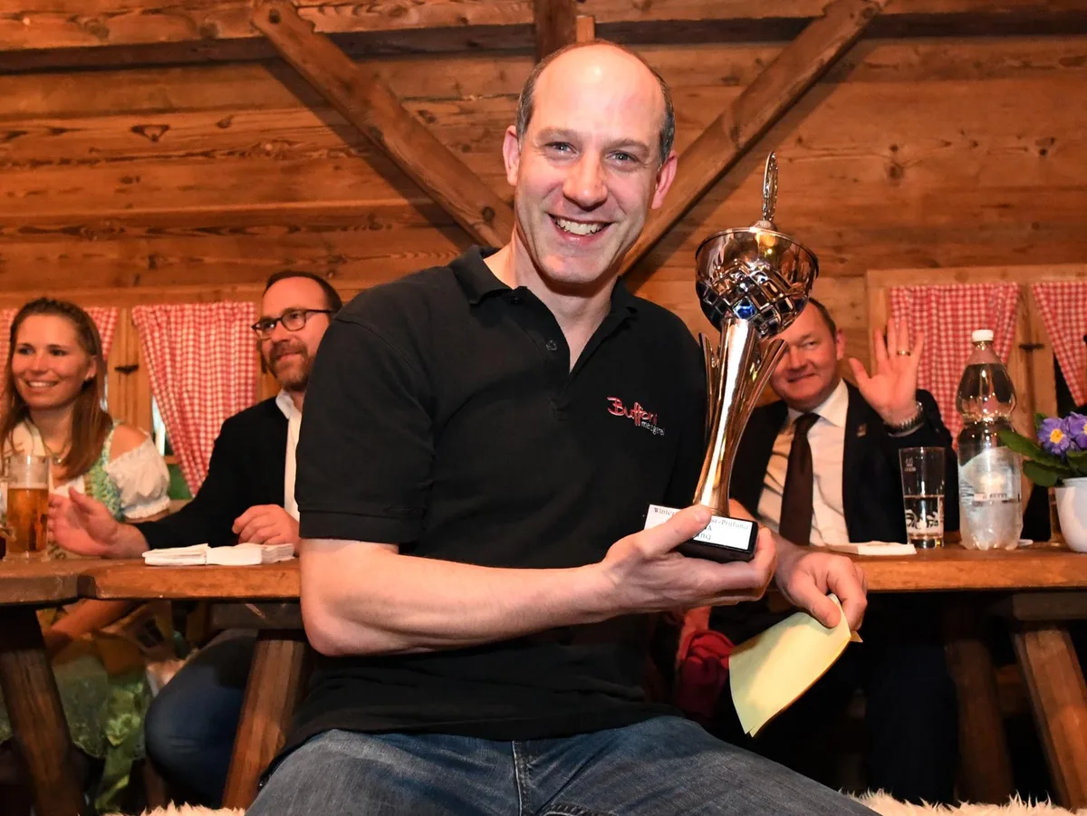 Mann mit einem Pokal in der Hand.